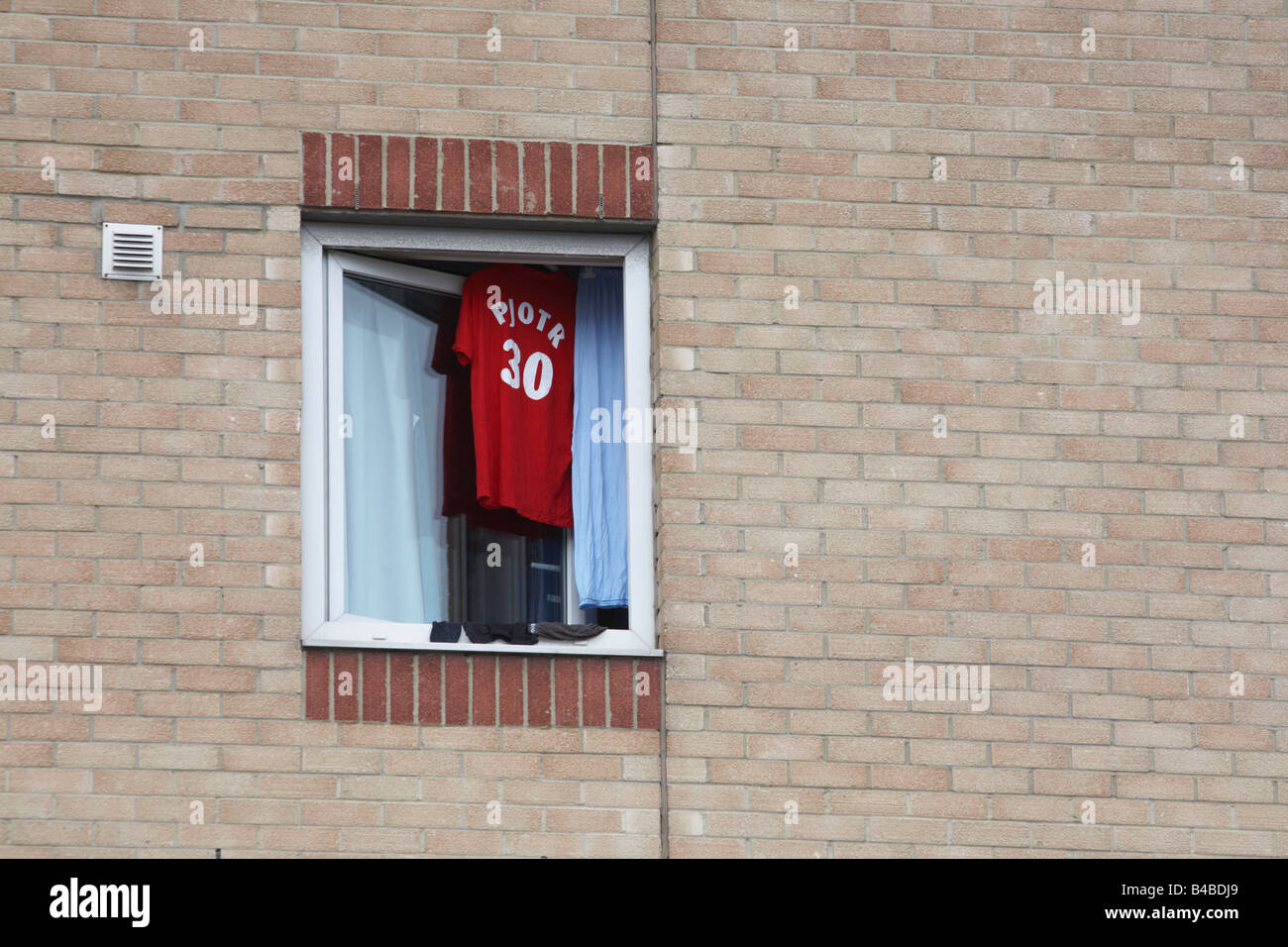 A Polish football shirt belonging to Piotr dries on a hangar in an open Ibis hotel window in industrial West Thurrock Stock Photo