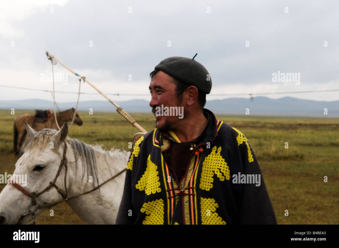 A Mongolian herder with his horse in the vast Mongolian grasslands ...