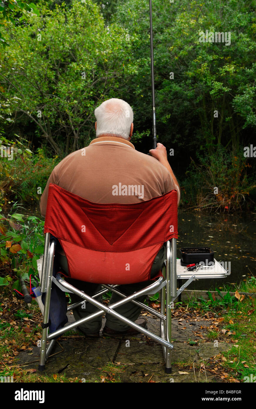 Man fresh water fishing at Barn Elm Lake, Barnes, west London UK Stock Photo