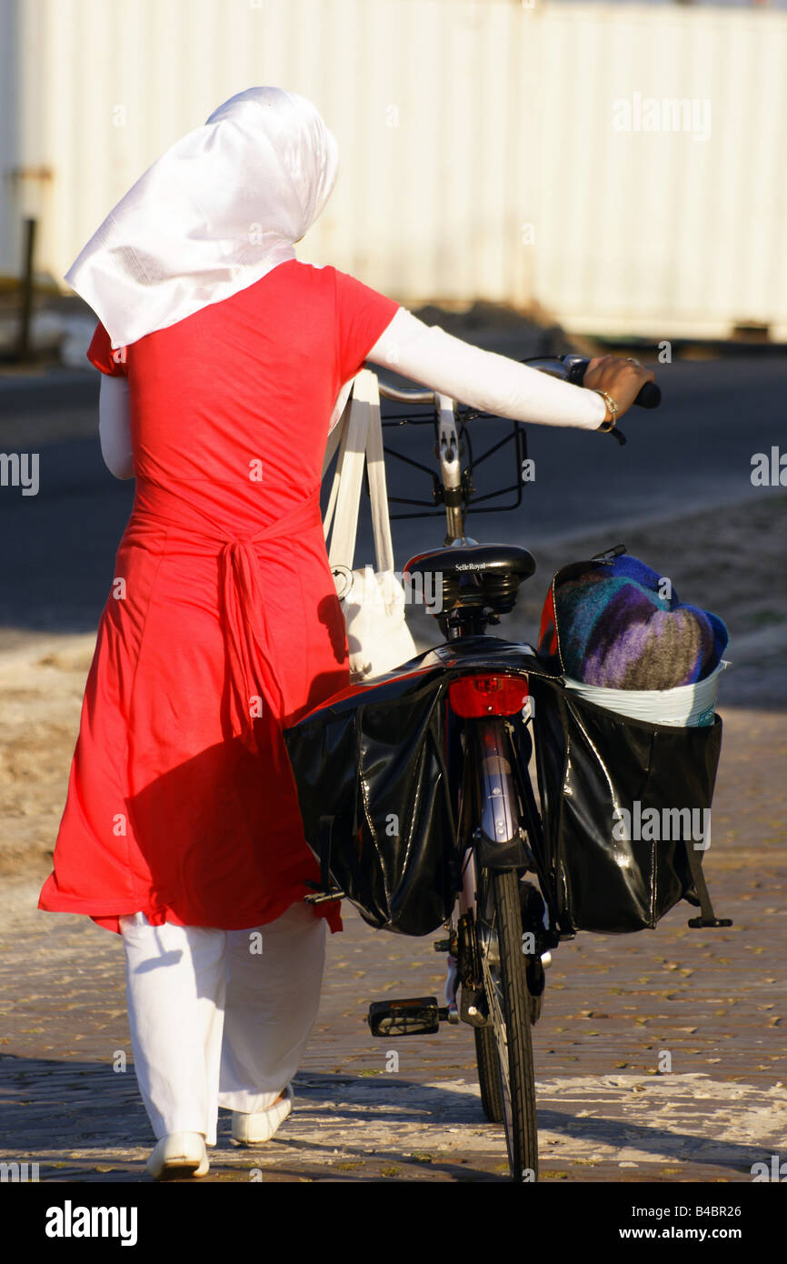 Moslim muslem woman pushing cycle bicycle dressed in traditional arab style with headscarf in Netherlands Stock Photo