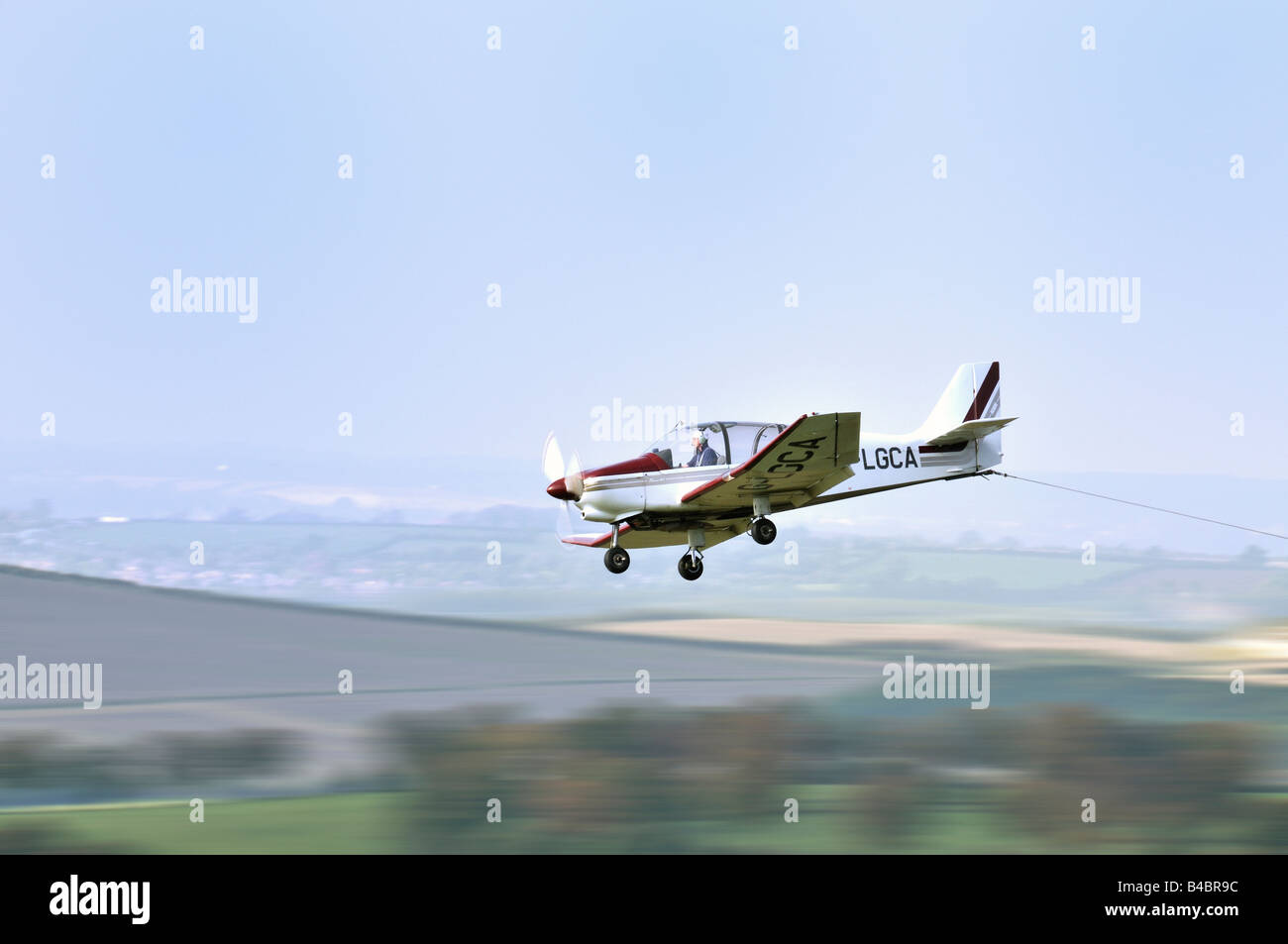 Light aircraft used to tow gliders showing trailing tow cable Stock Photo