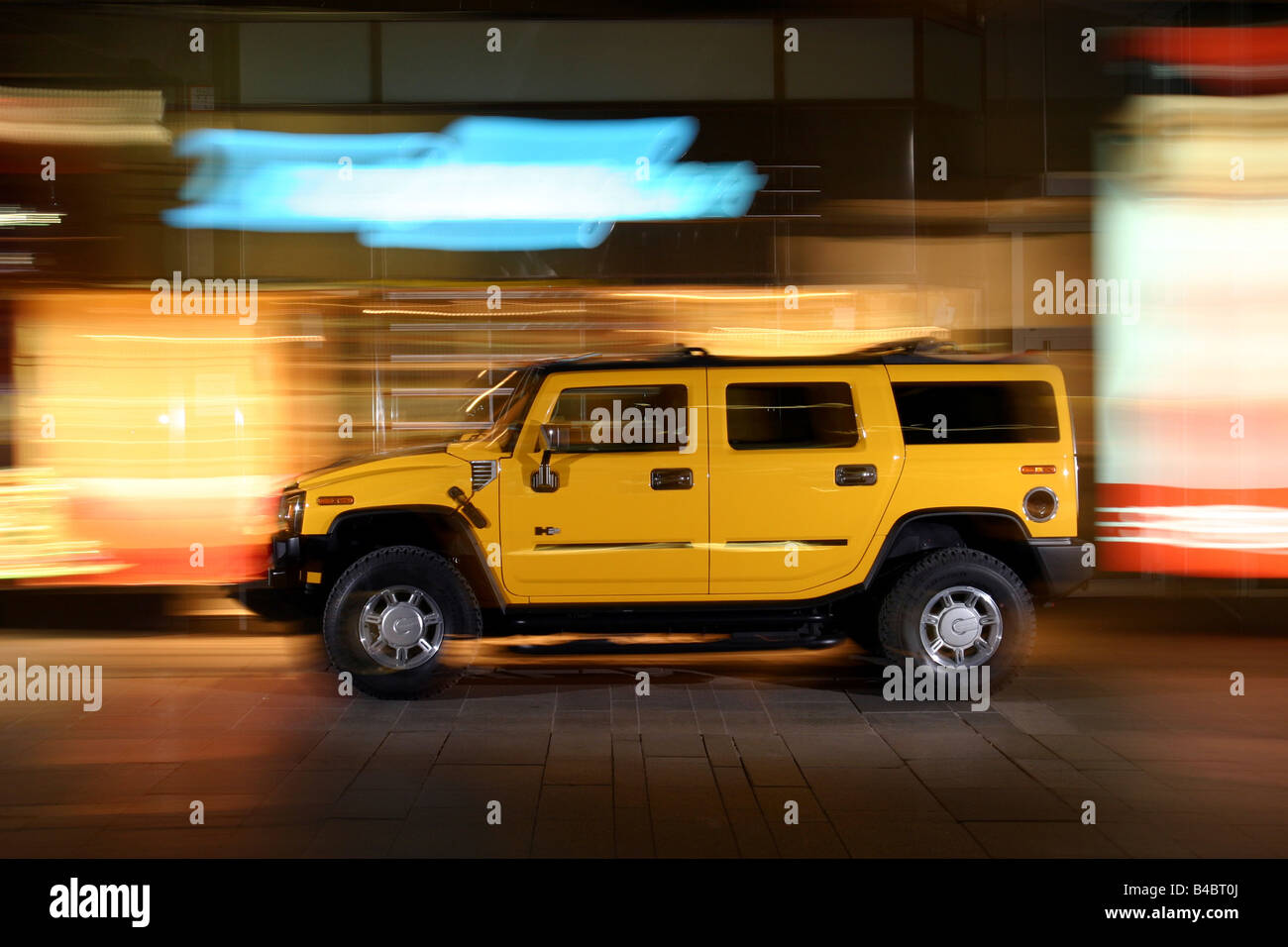 Car, Chevrolet Hummer H2, cross country vehicle, model year 2001-, yellow, driving, side view, City, at night, photographer: Han Stock Photo