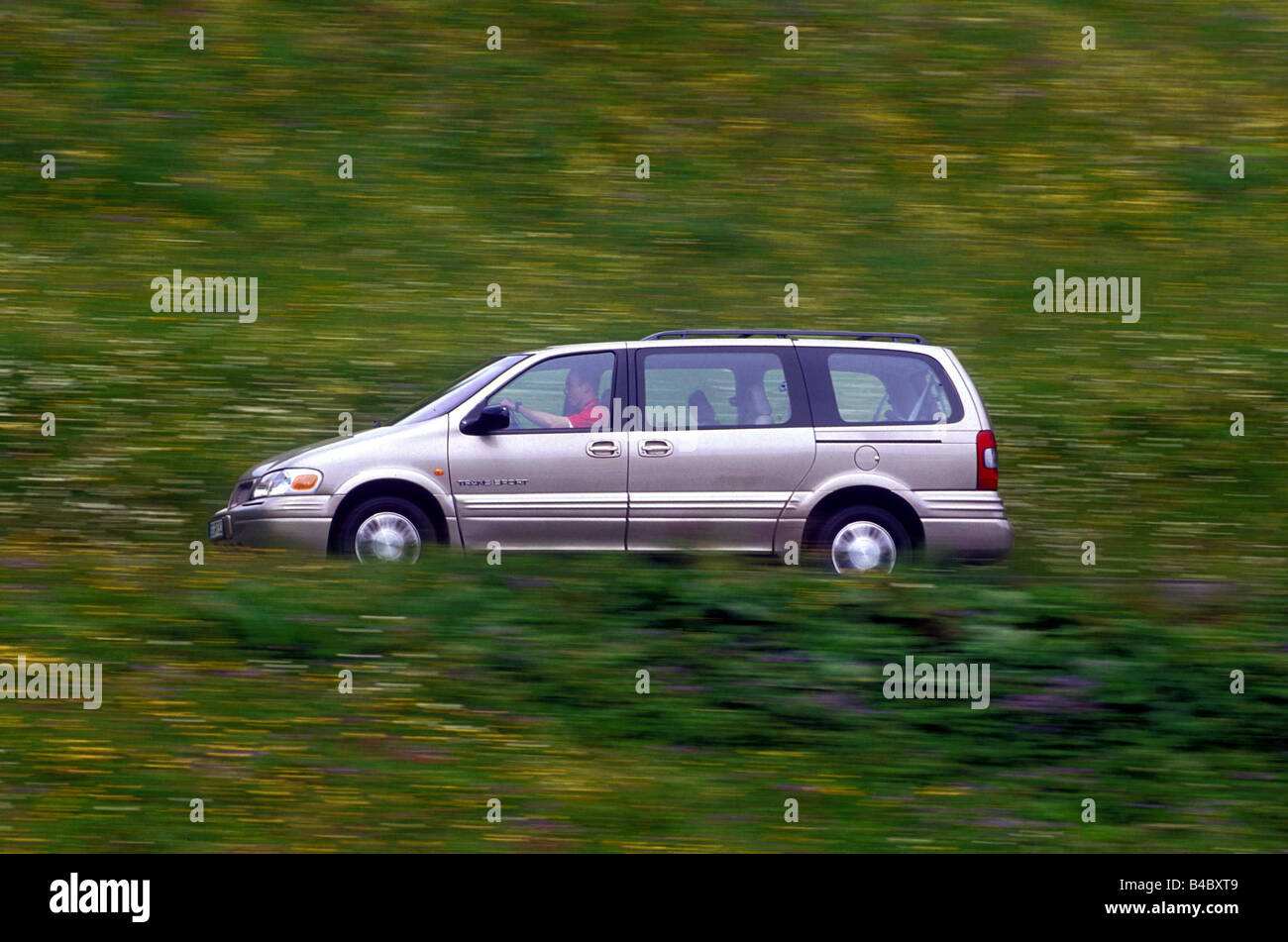 Car, Chevrolet Trans Sport, Van, model year 1996-2002, silver-beige, fawn, side view, driving, country road Stock Photo