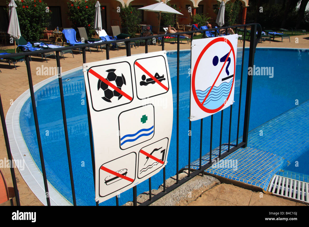 A group of safety signs in front of a swimming pool Stock Photo