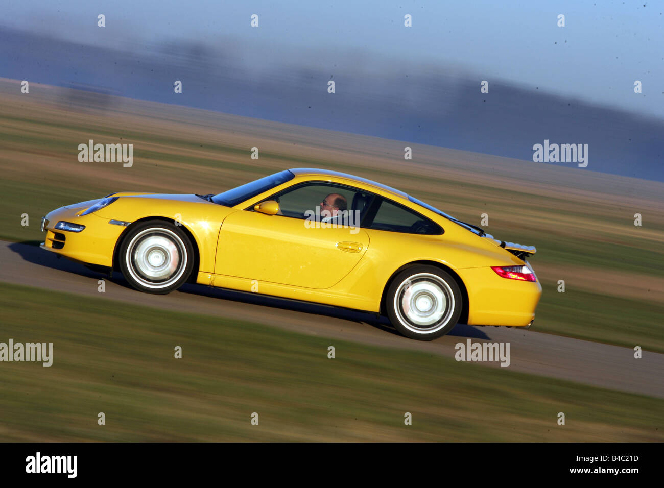 Car, Porsche 911 Carrera S, coupe/Coupe, model year 2004-, roadster, yellow, driving, side view, country road, photographer: Han Stock Photo