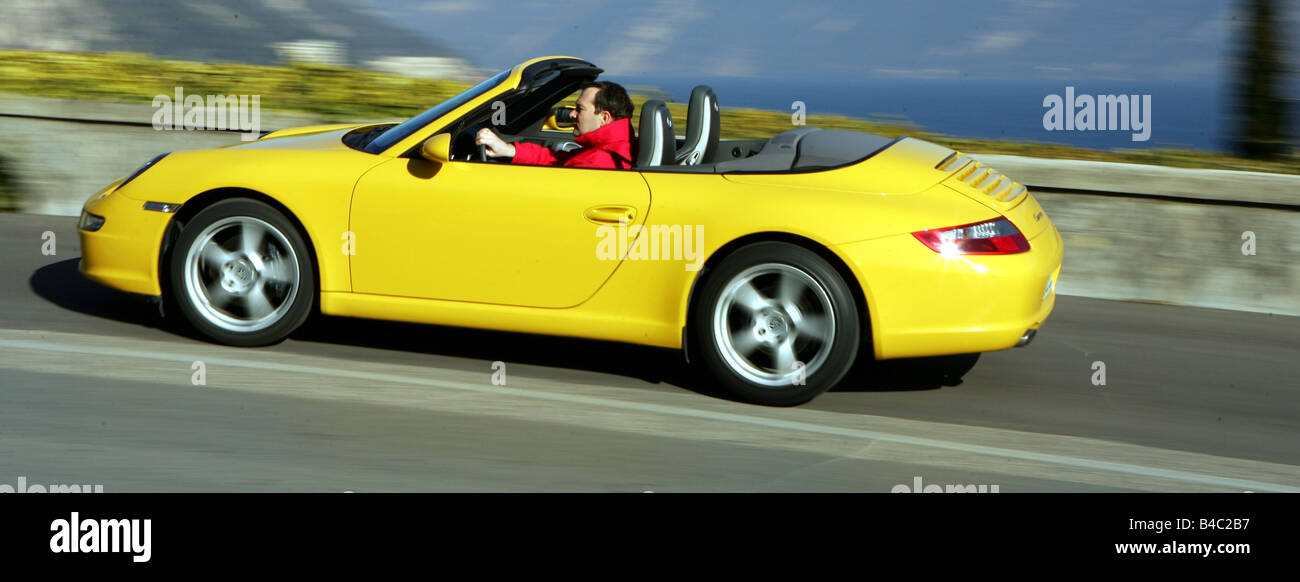 Car, Porsche 911 Carrera Convertible, model year 2005-, yellow, driving, side view, open top, country road, landsapprox.e, photo Stock Photo