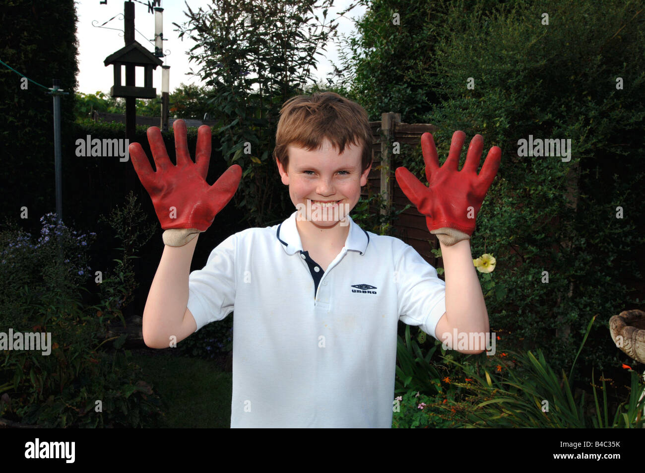 A 13yr Old Boy Wearing Red Rubber Gardening Gloves . Stock Photo