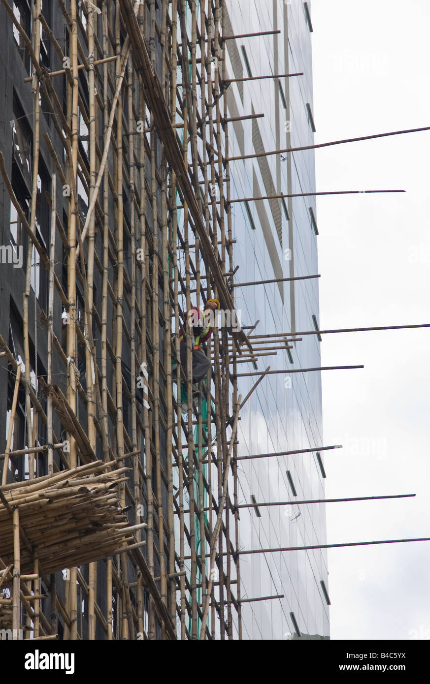 Construction worker leaning out from bamboo scaffold, Central, Hong Kong Stock Photo