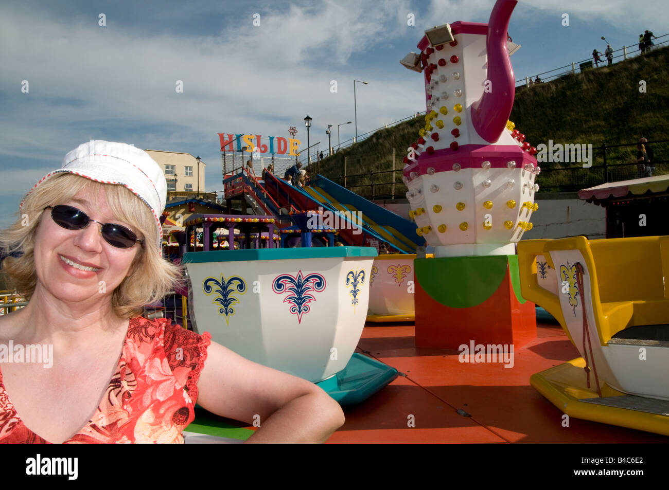 Smiling middle aged woman in front of Seaside ride in Cromer Norfolk England Stock Photo