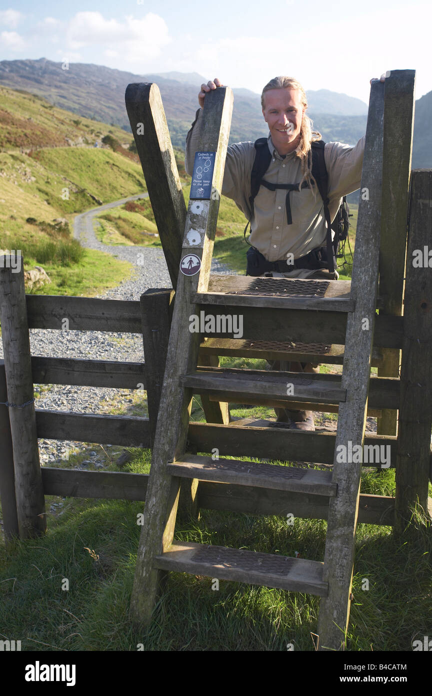 Man climbing over ladder stile at the head of  Nant Gwynant Valley, Snowdonia, Wales Stock Photo
