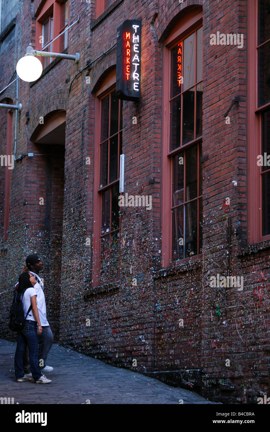 A couple examines the Gum Wall in Seattle's Post Alley at Pike Place Market. Stock Photo