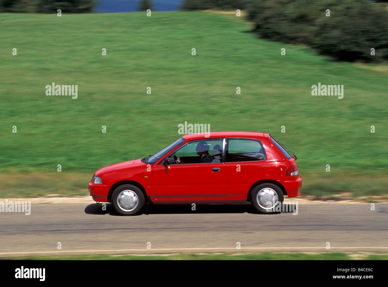 Car, Daihatsu Charade, model year 1993-, red, small approx., Limousine, driving, side view, country road, photographer: Hans Die Stock Photo