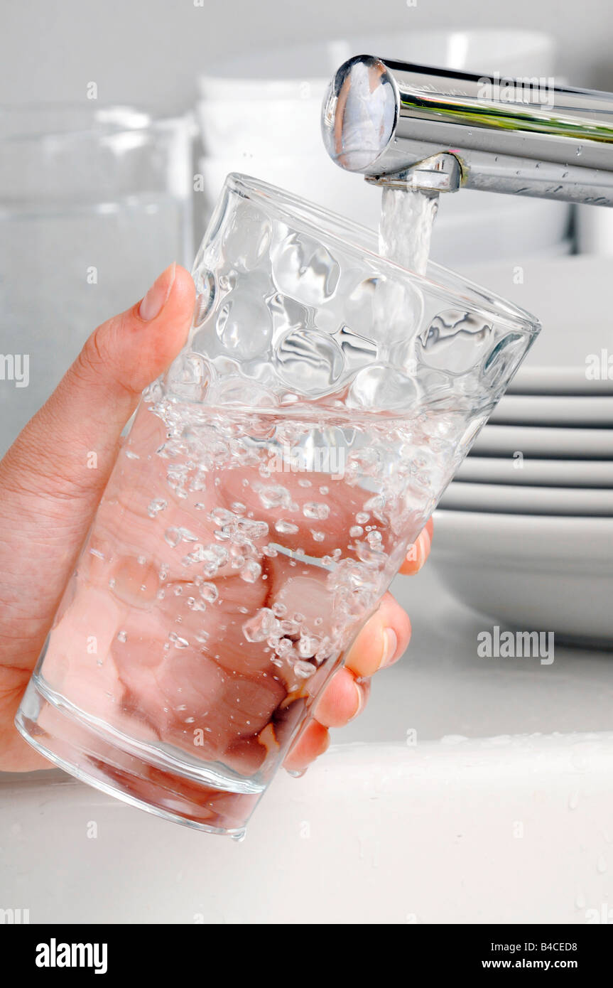 WOMAN FILLING GLASS TUMBLER WITH TAP WATER Stock Photo
