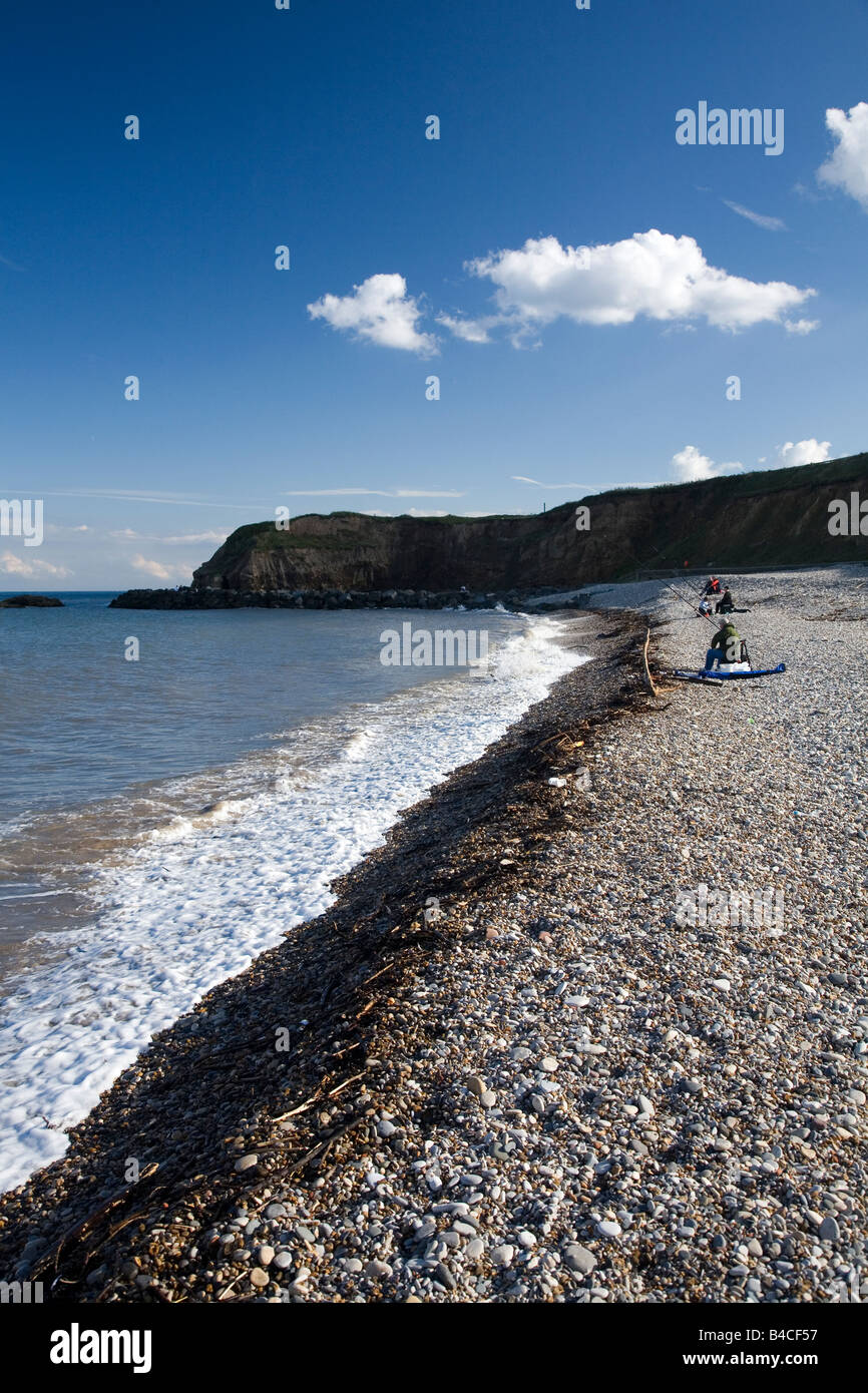 People sit on a beach on the northeast coast of England and fish. This is Seaham Harbour on a fine autumn day. Stock Photo