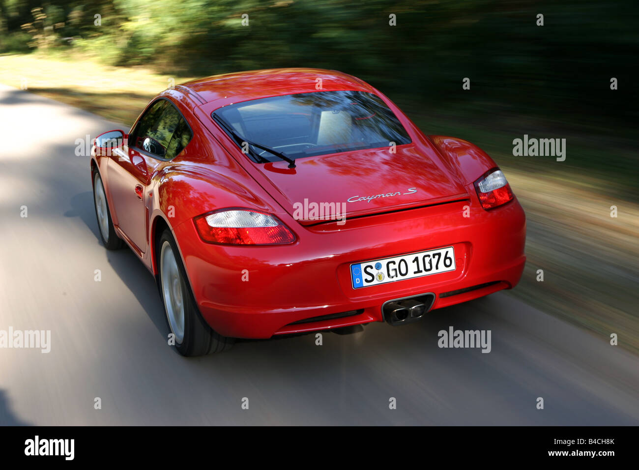 Porsche Cayman S, roadster, model year 2005-, red, driving, diagonal from the back, rear view, country road Stock Photo