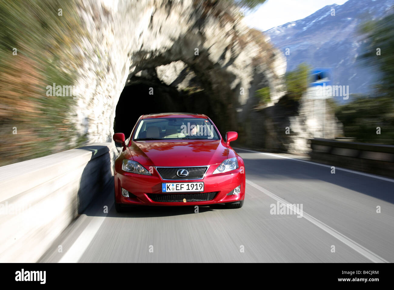 Lexus IS 250, model year 2005-, red, driving, diagonal from the front, frontal view, Tunnel, country road, Mountains Stock Photo