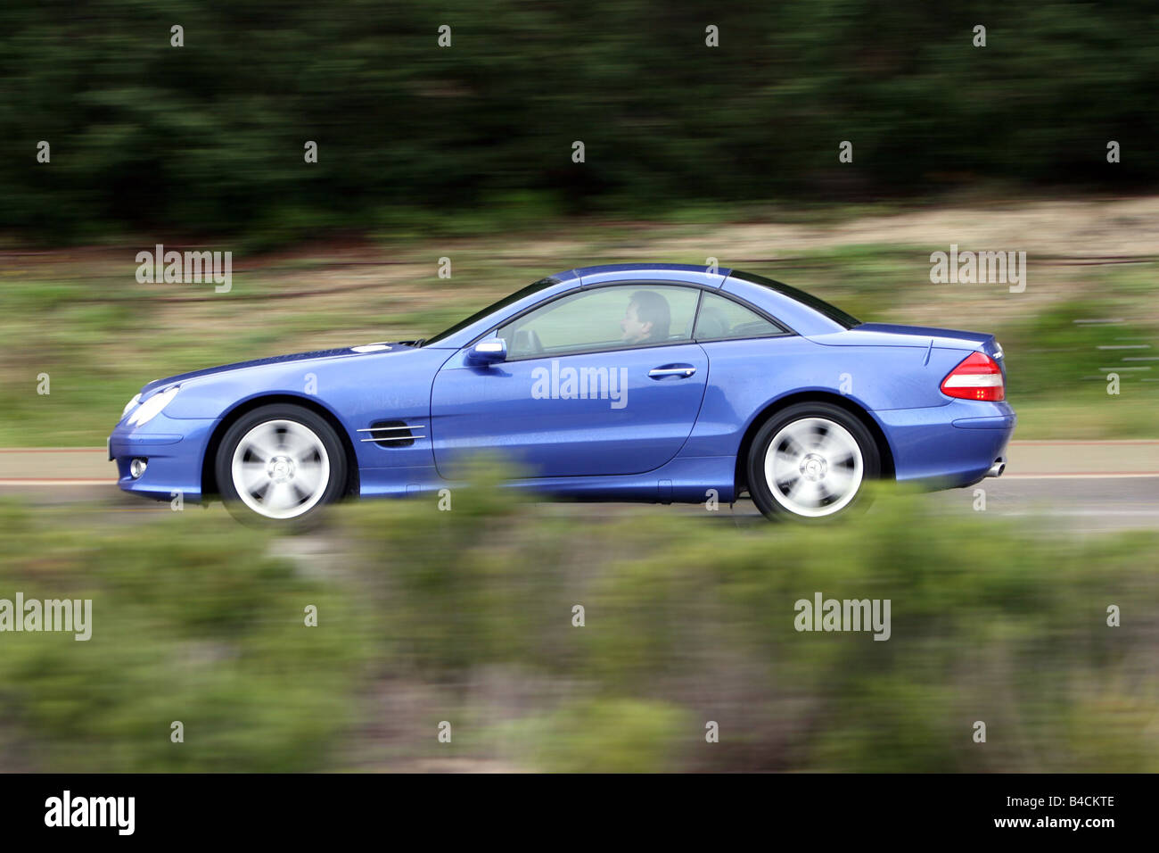 Mercedes SL 500, model year 2005-, blue moving, side view, country road, closed top Stock Photo