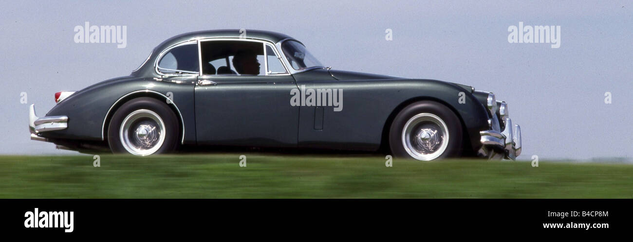 Jaguar XK 150 coupe, model year 1957-1961, anthracite, driving, side view, country road Stock Photo