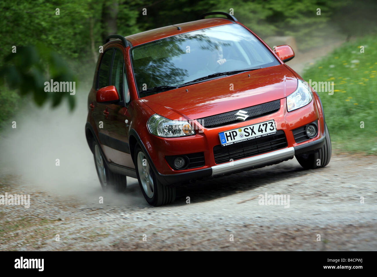 Car, Suzuki SX4 1.9 DDiS-AWD, model year 2006-, orange , driving, diagonal from the front, frontal view, country road Stock Photo