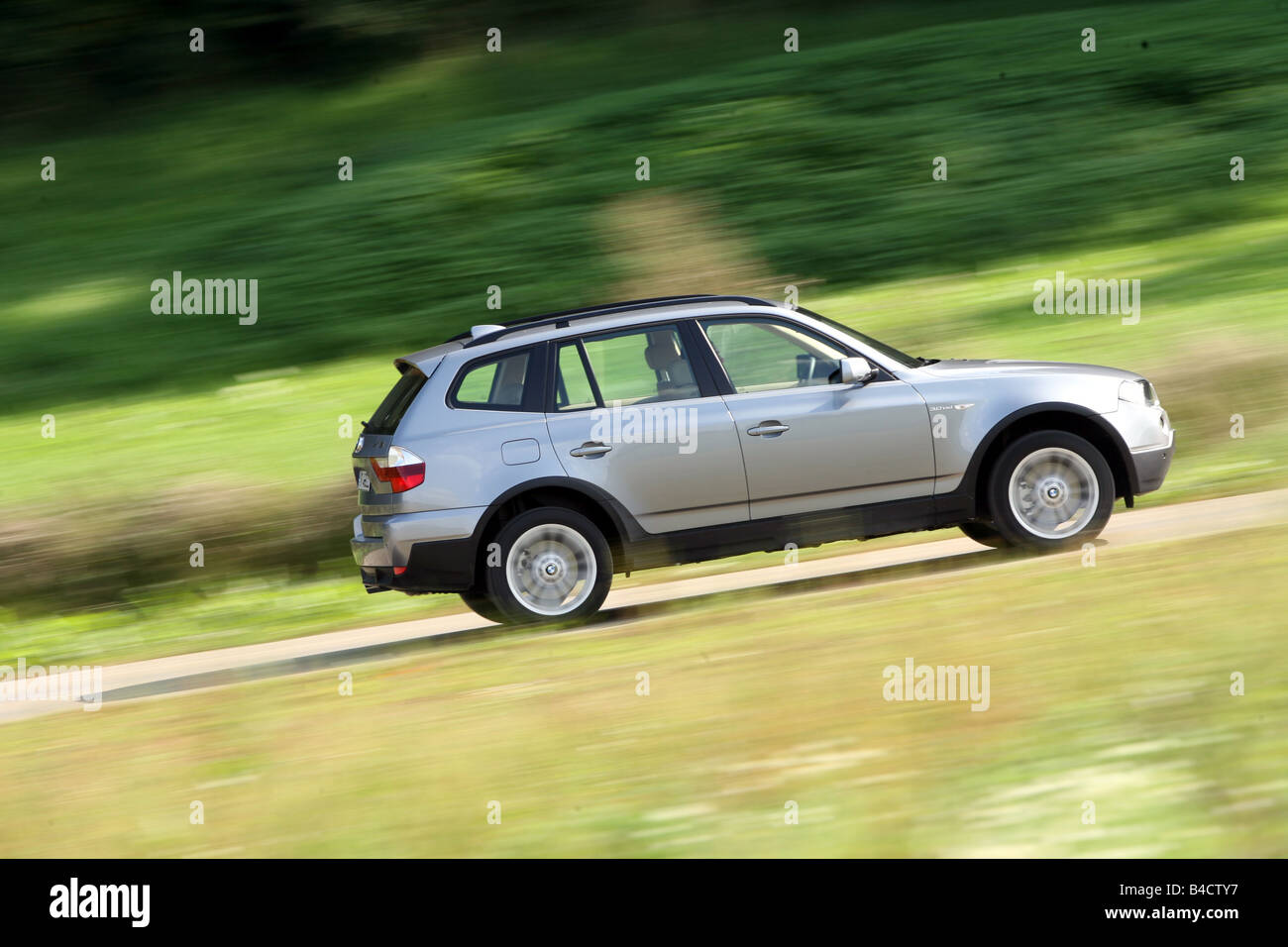 BMW X3 3.0 sd, model year 2006-, anthracite, driving, side view, country road Stock Photo