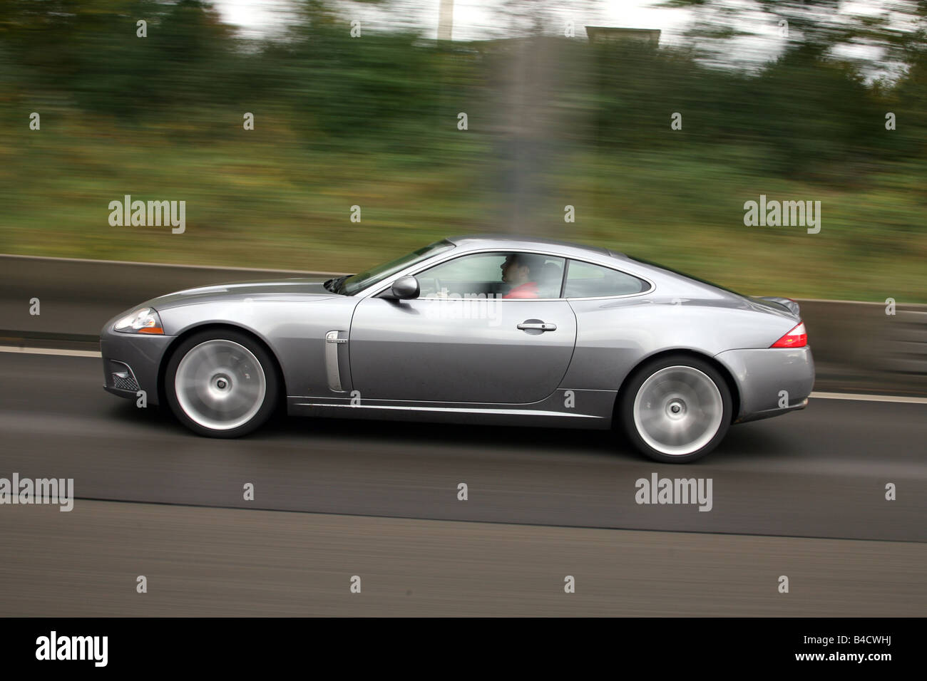 Jaguar XKR coupe, model year 2006-, anthracite, driving, side view, country road Stock Photo