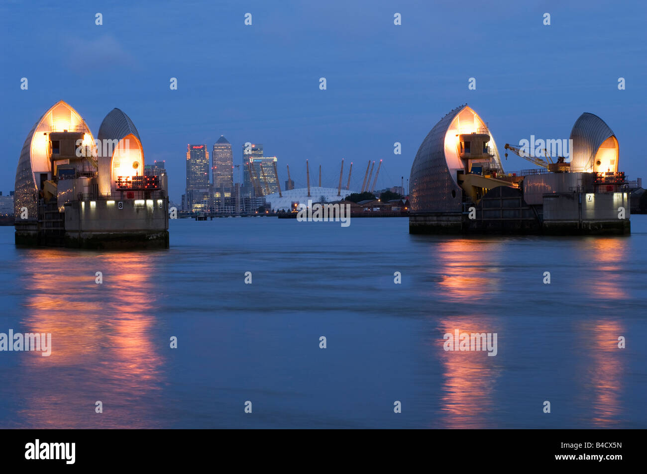 London England The Thames Flood Barrier with The Mellenium Dome and Canary Wharf in the background at dusk Stock Photo