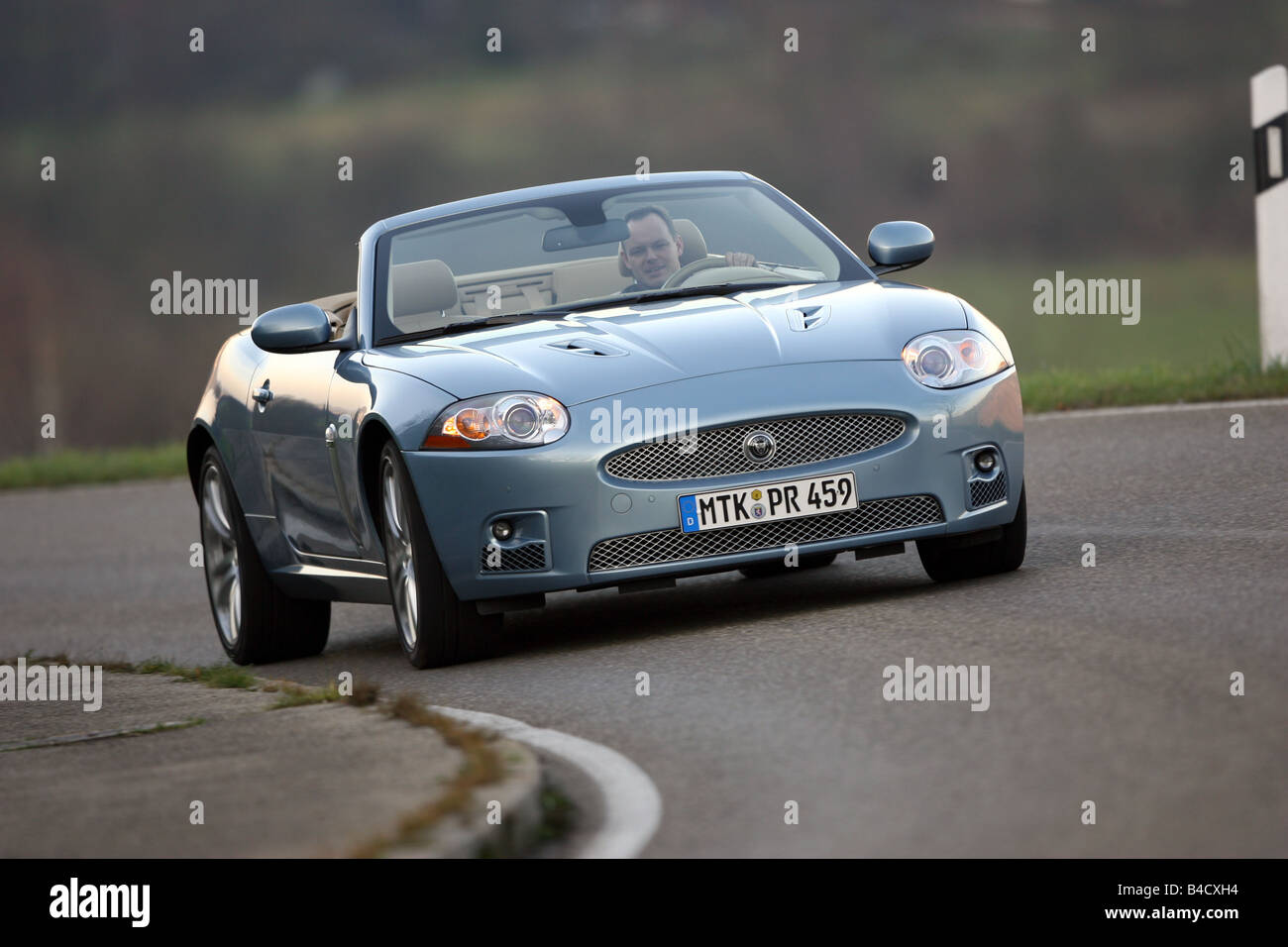Jaguar XKR Convertible, model year 2006-, silver, driving, diagonal from the front, frontal view, country road, open top Stock Photo