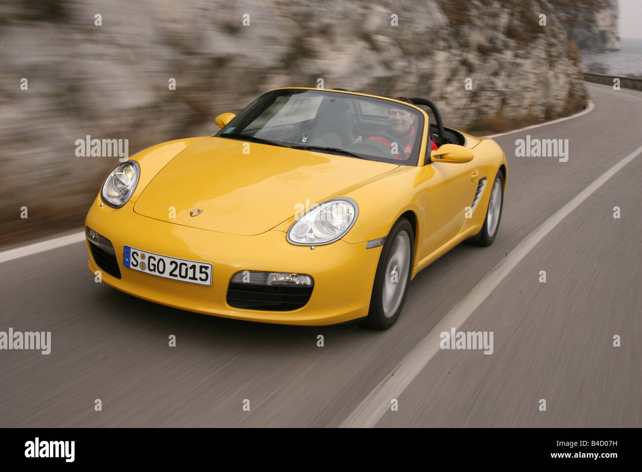 Porsche Boxster Sportpaket, model year 2004-, yellow, driving, diagonal from the front, frontal view, country road, Serpentinen, Stock Photo