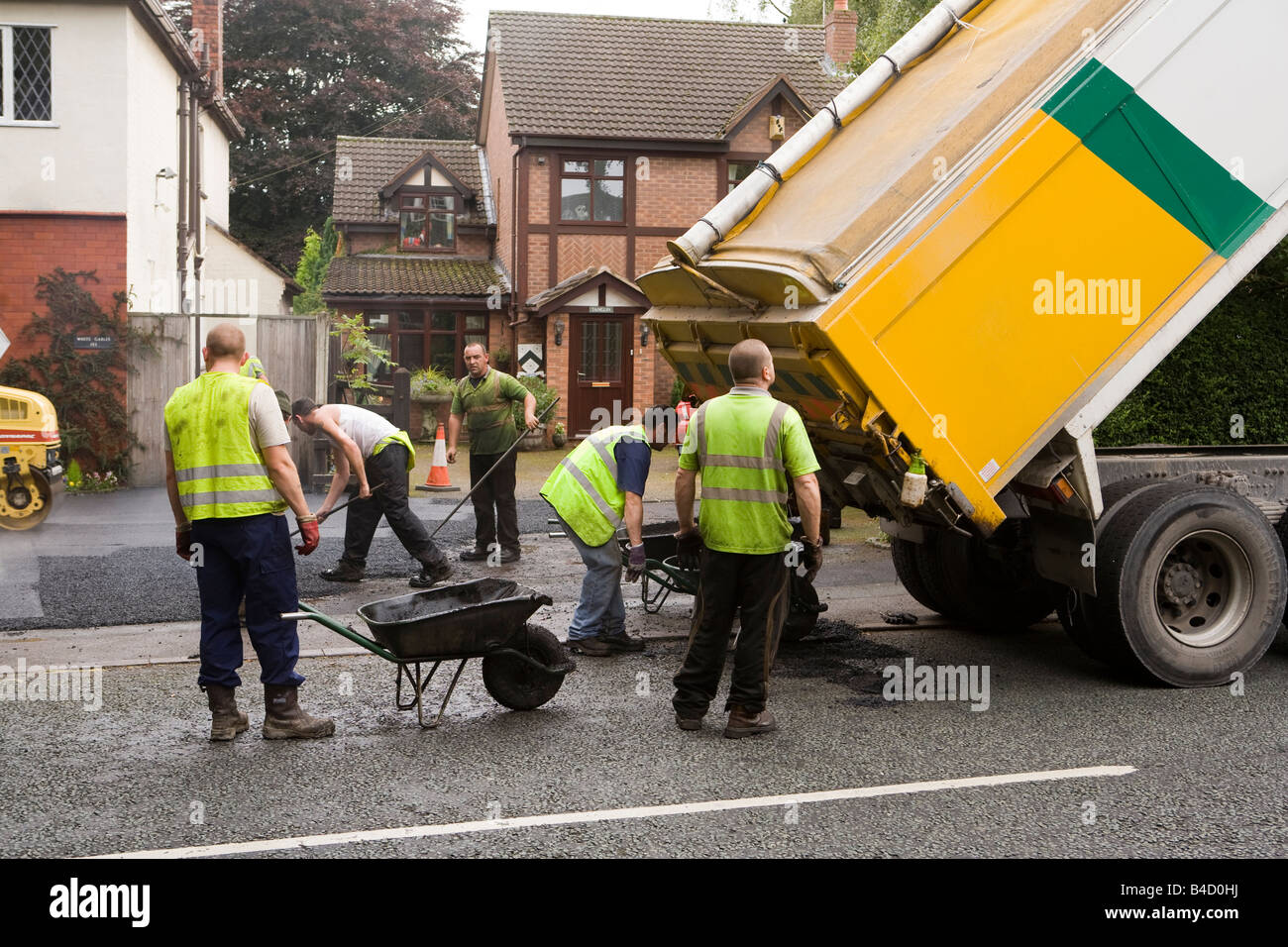 Home improvements gang of workers laying new tarmac domestic drive Stock Photo
