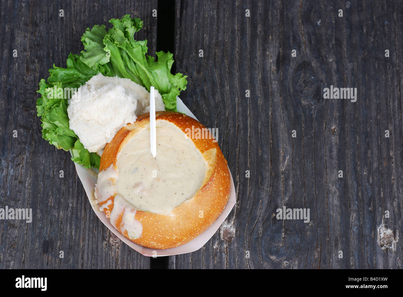 Sourdough bread bowl filled with clam chowder on a dock railing in