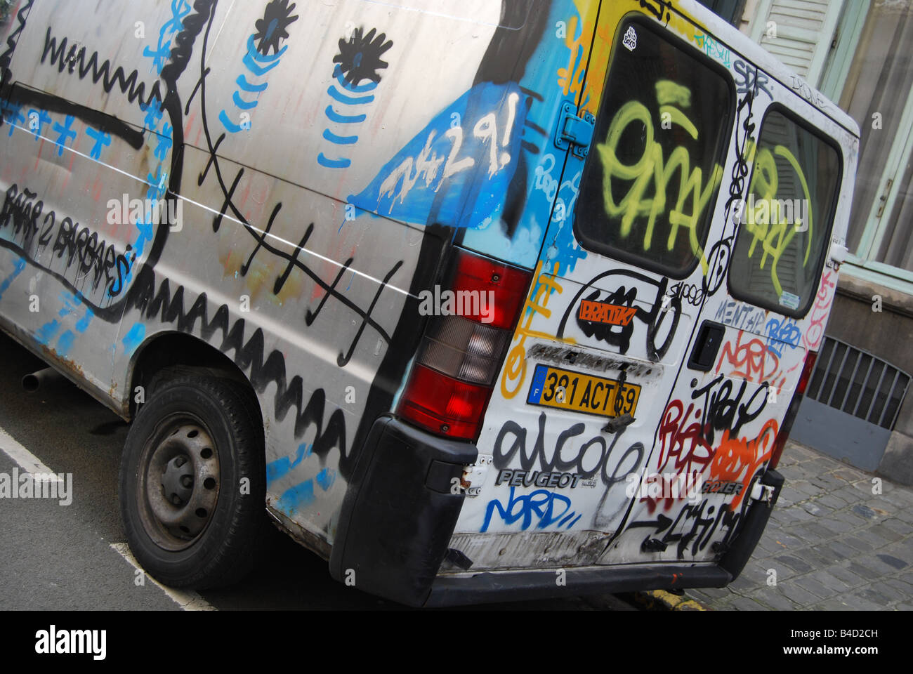 Urban street scene with vandalised graffiti covered minivan parked along the road in Lille France Stock Photo