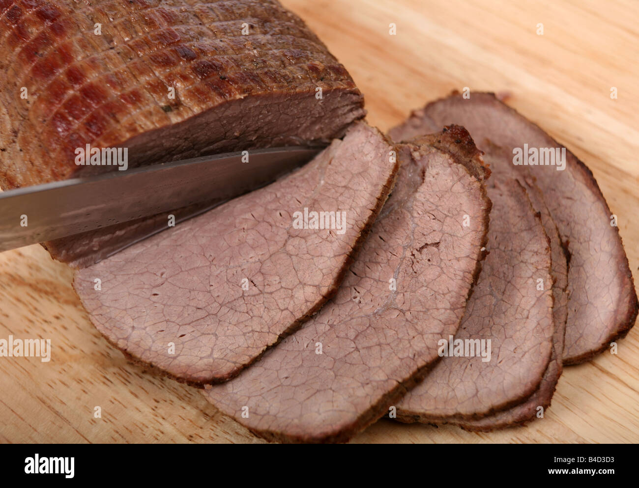 A beef round joint being sliced for serving after being braised pot