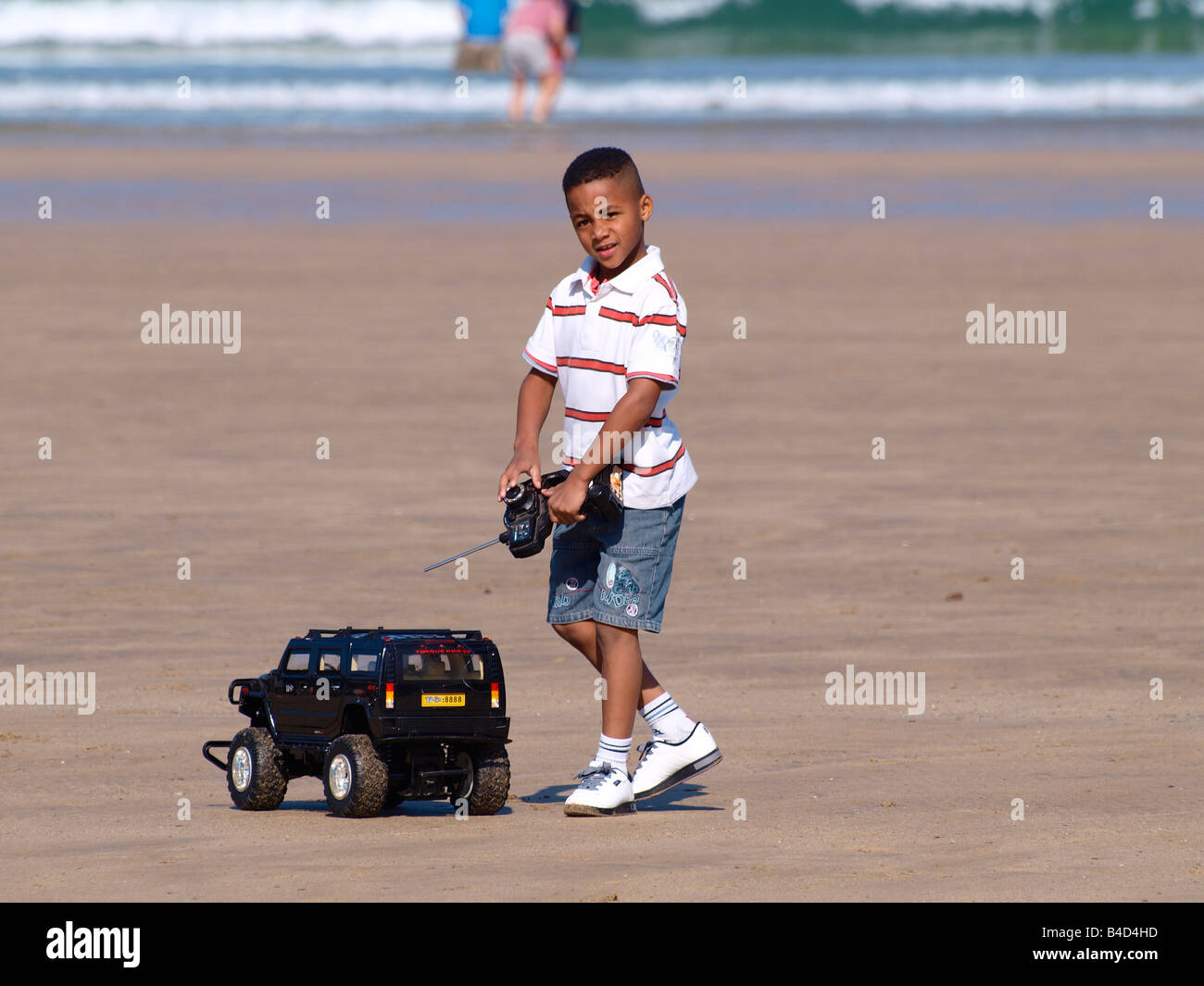 Young coloured boy playing with a remote controlled truck at the beach Stock Photo