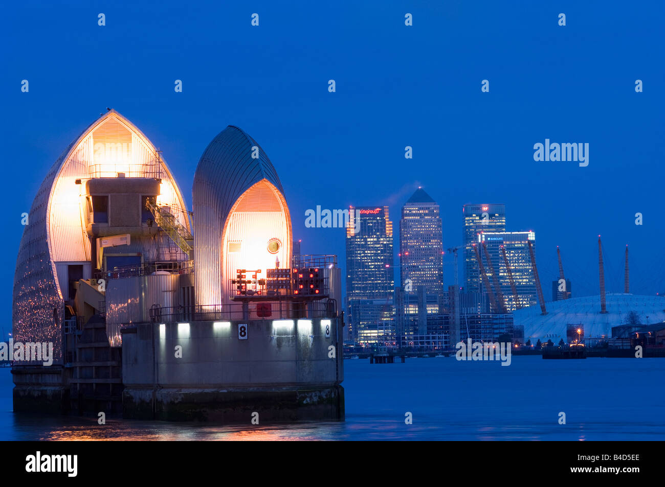 London England The Thames Flood Barrier with The Mellenium Dome and Canary Wharf in the background at dusk Stock Photo