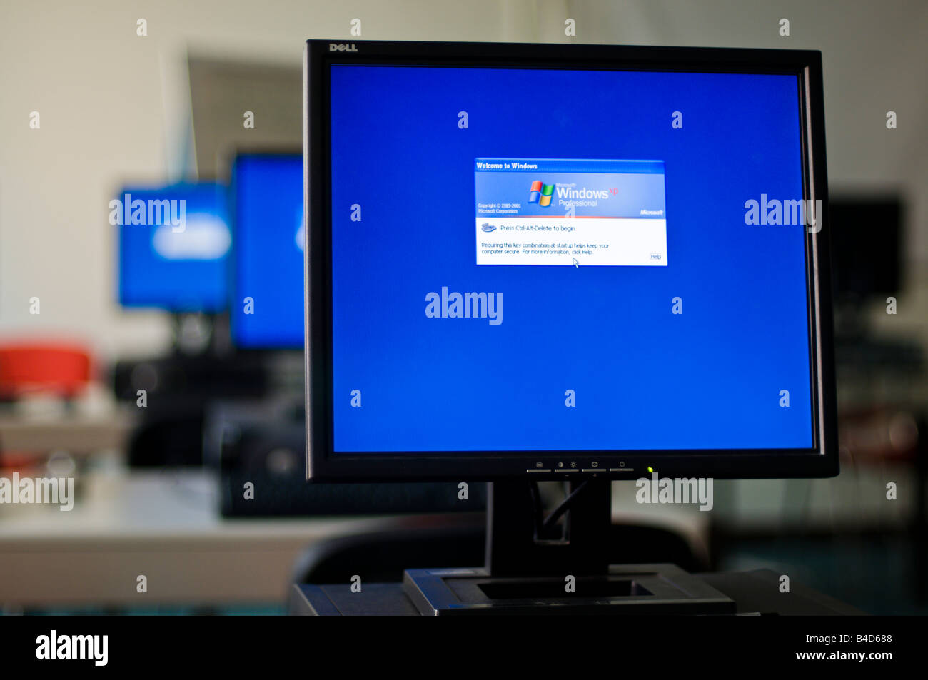 Three Dell monitors in a training room showing windows log-on screen Stock Photo