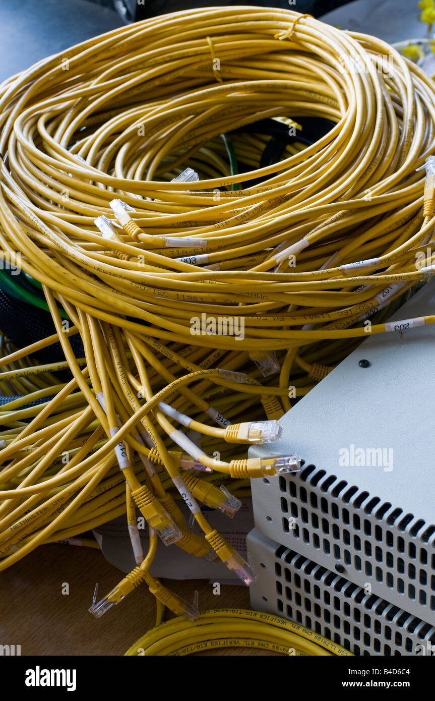 Jumble of yellow ethernet cables beside two network devices. Stock Photo