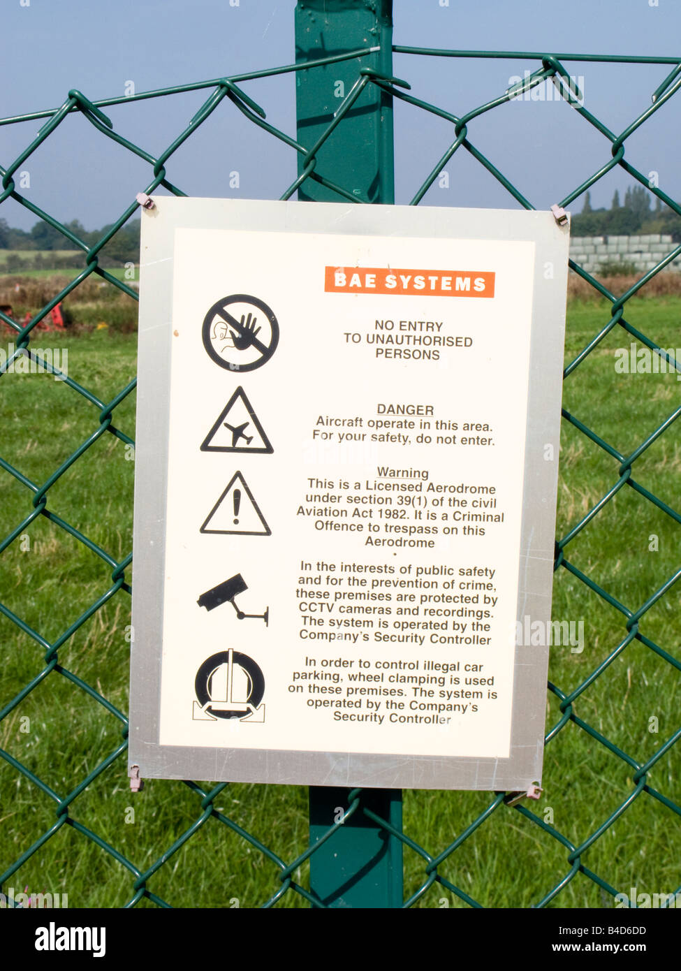 Defence Woodford security warning notice on BAe Systems airfield perimeter fence Stock Photo
