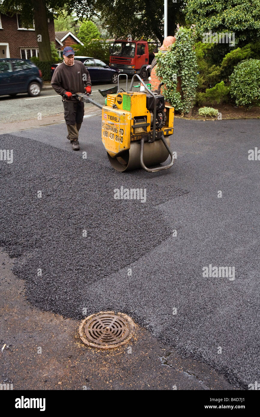 Home improvements gang of workers laying new tarmac domestic drive hot rolling flat Stock Photo
