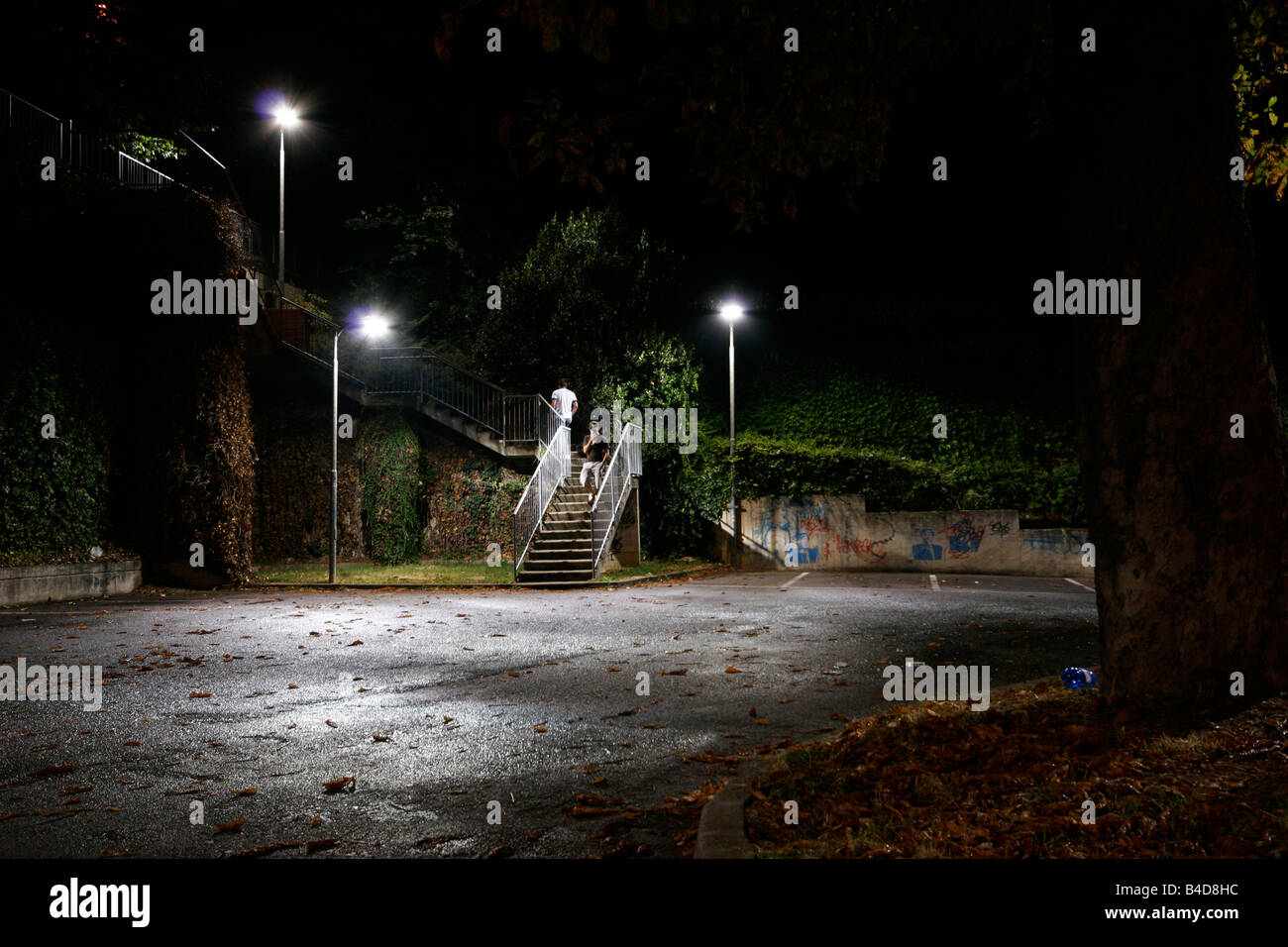 Empty car parking with two men walking in the night.  Moncalieri, Turin, Italy. Stock Photo