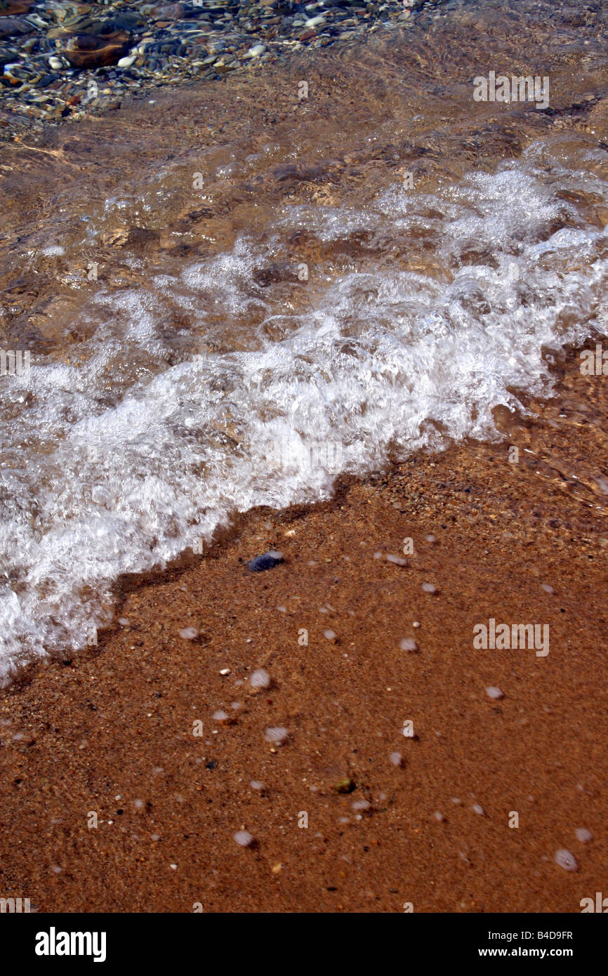 SMALL WAVES LAPPING THE GREEK SHORELINE. Stock Photo