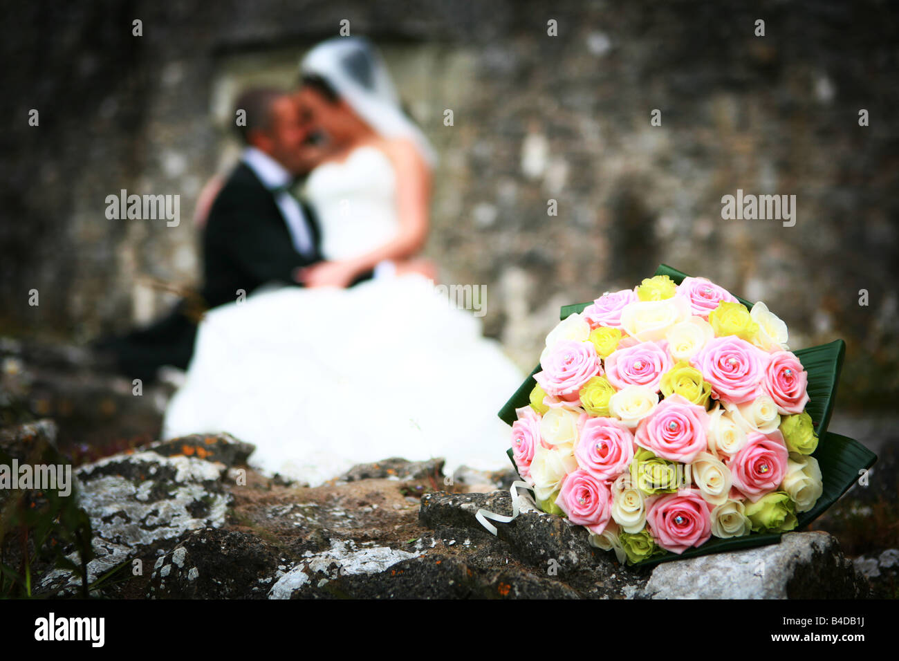 Closeup of brides colourful flower bouquet with bride and groom kissing ...