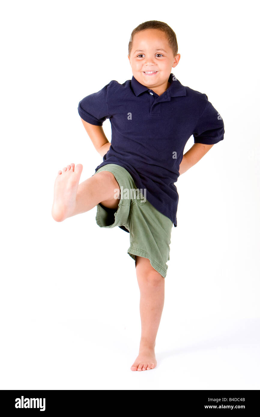 Happy mixed race boy with hands on hips and kicking a leg Stock Photo