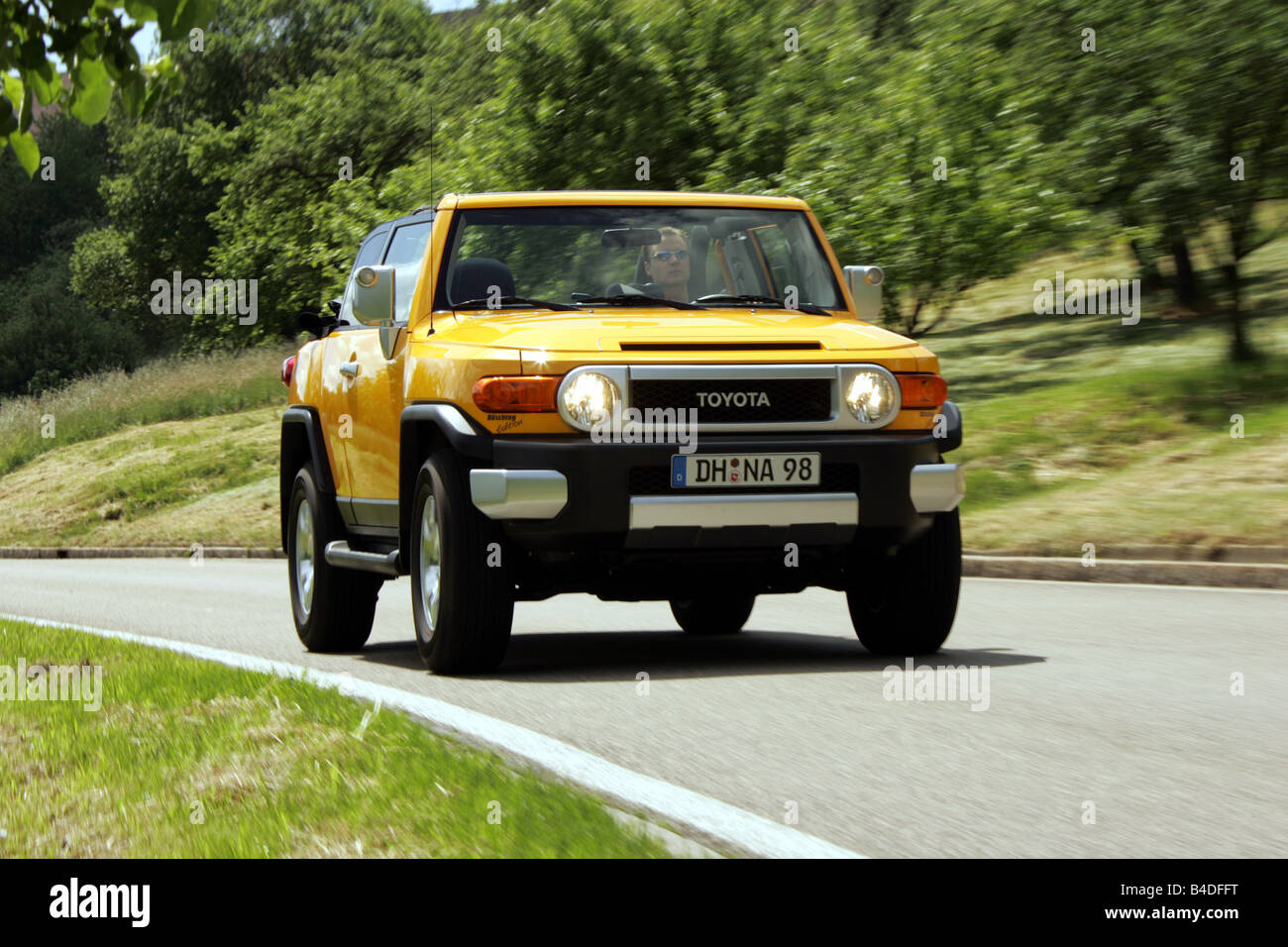 Toyota FJ Cruiser, built by Büsching , model year 2007-, yellow, driving, diagonal from the front, frontal view, country road Stock Photo