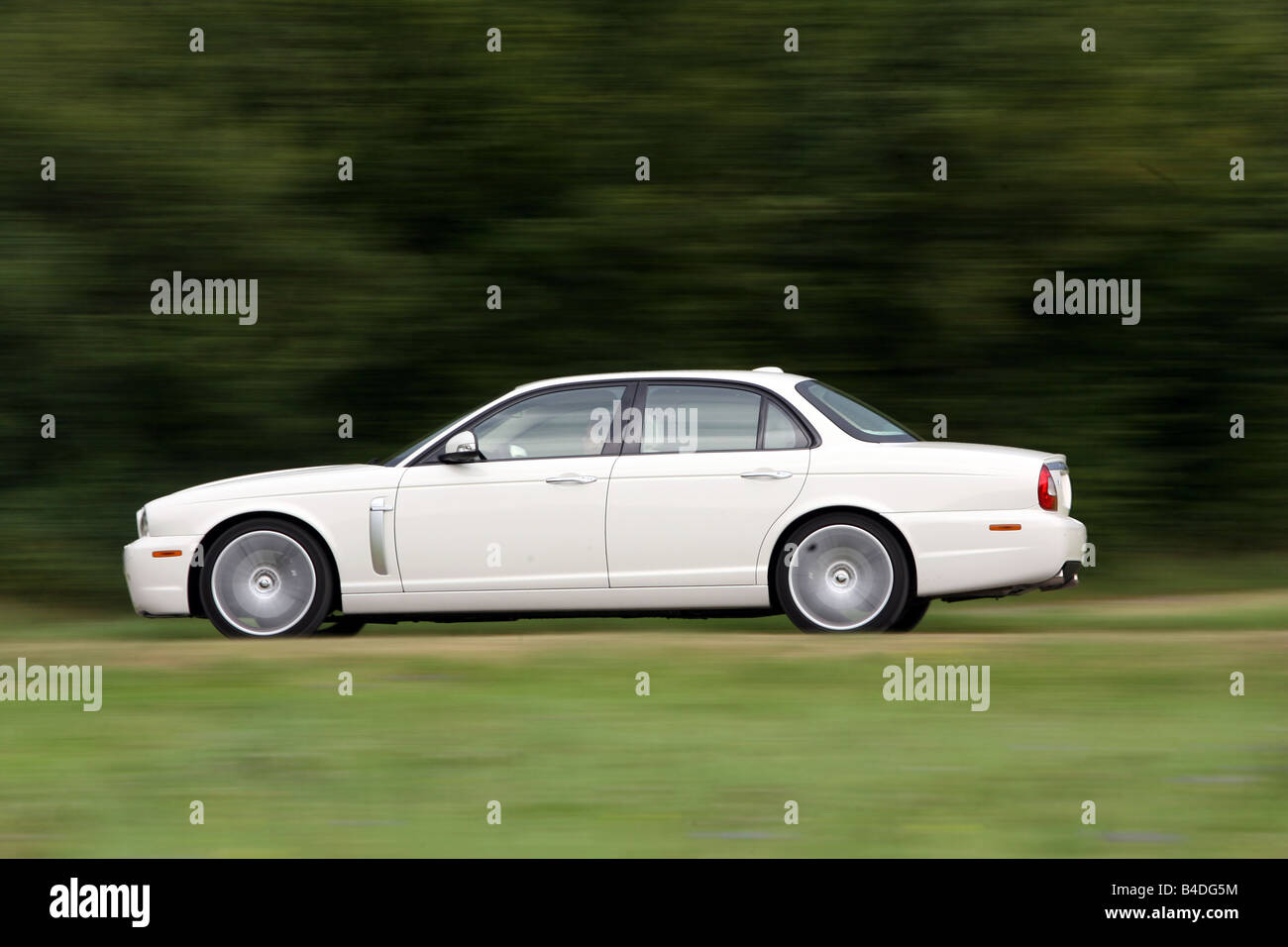 Jaguar XJR model year 2007, white, driving, side view, country road Stock Photo