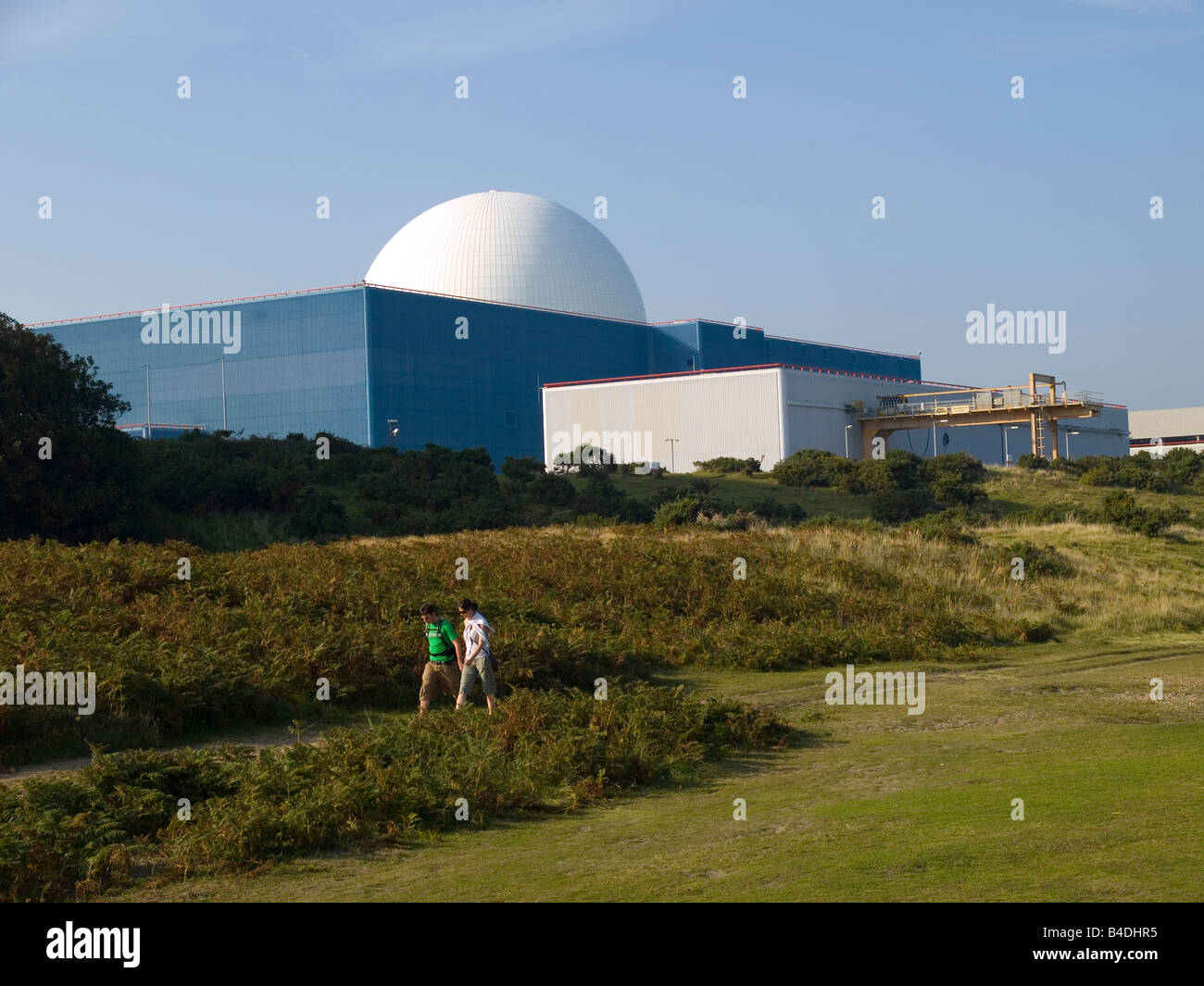 A young couple walk on the heathland in front of the Nuclear Power station Sizewell Suffolk UK Stock Photo