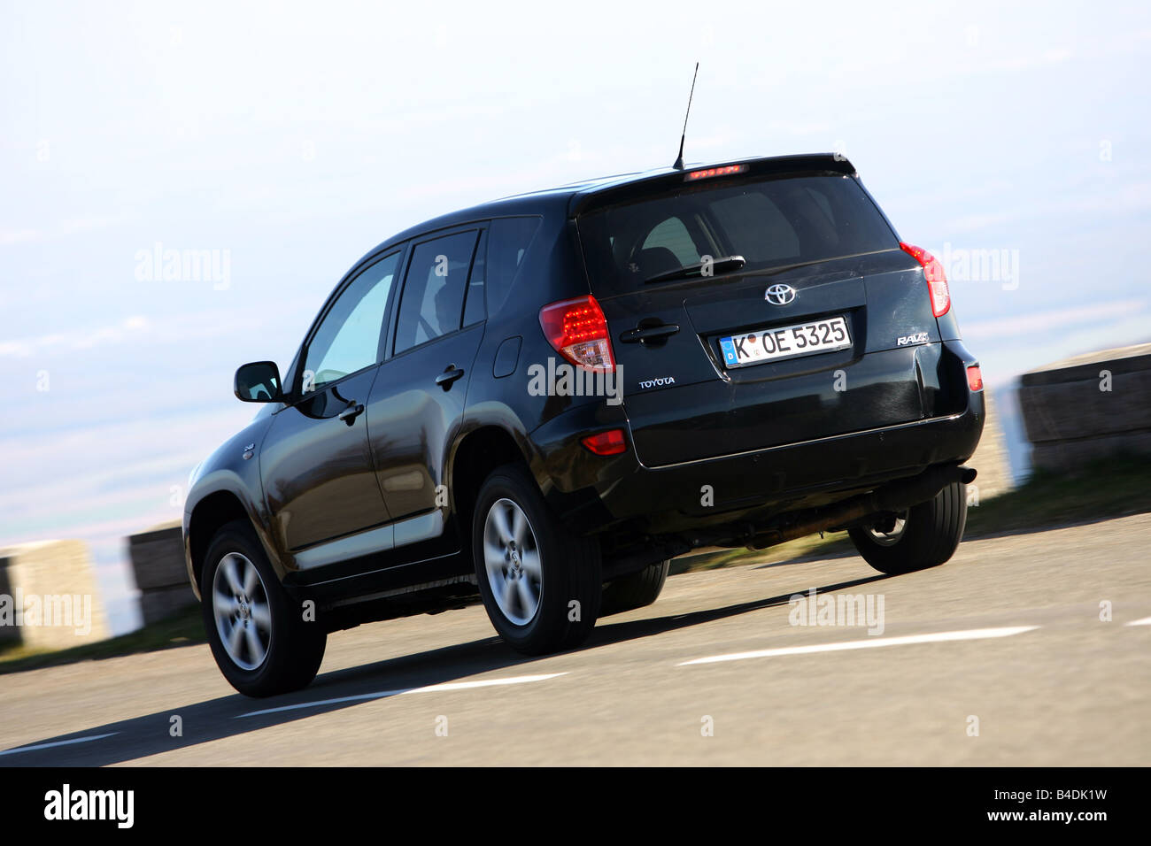 Toyota RAV4 2.2 D-4D Cross Sport, model year 2006-, black, driving, diagonal from the back, rear view, country road Stock Photo