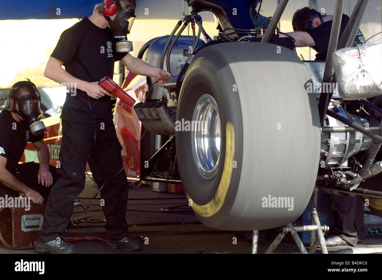 top fuel dragster mechanic using a timing light to set the ignighton during a warm up in the pits Stock Photo
