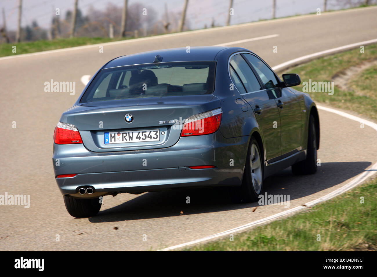 BMW 525d, model year 2006-, anthracite, driving, diagonal from the back, rear view, country road Stock Photo