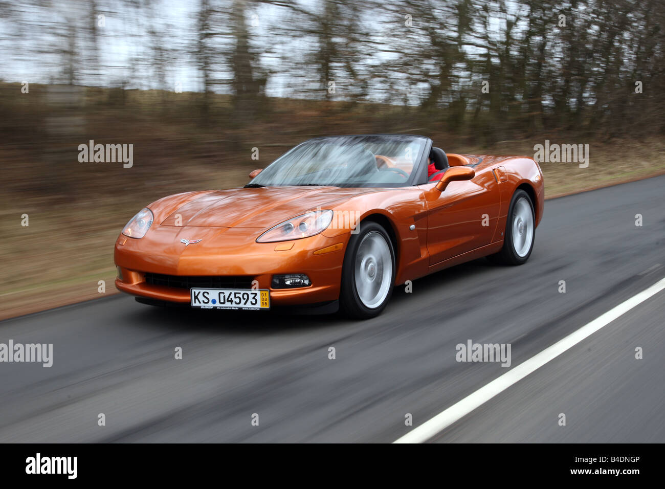 Corvette C6, rust-red model year 2008, orange -metallic, driving, diagonal from the front, frontal view, country road, open top Stock Photo