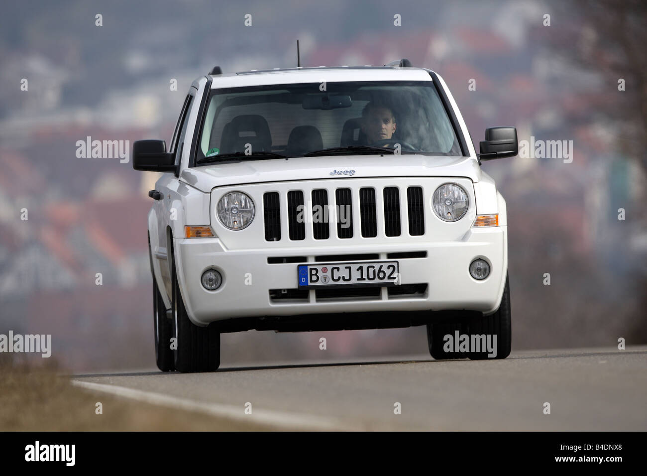 Jeep Patriot, model year 2008-, white, driving, diagonal from the front, frontal view, country road Stock Photo